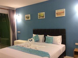 Habitación de hotel con cama, paredes azules y tres cuadros enmarcados.