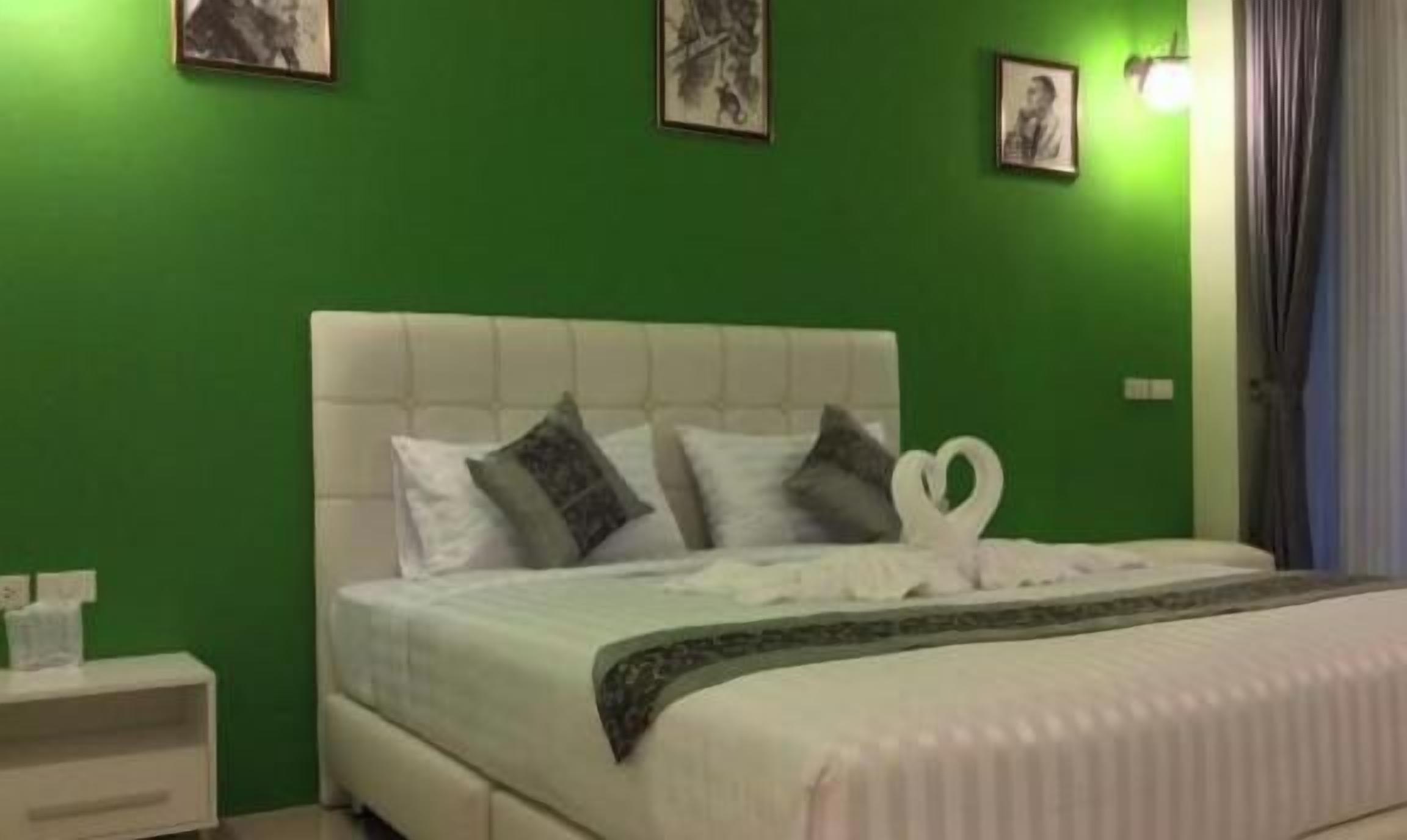 A bedroom with a bed, pillows, a nightstand, and green walls.