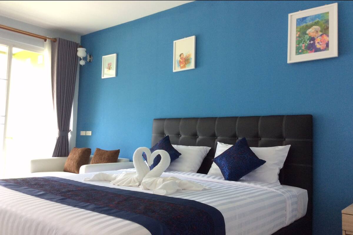 Ett hotellrum med en stor säng, blå väggar och inramade tavlor på väggen.