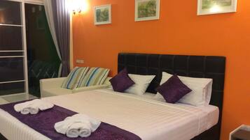 A hotel room with a large bed, a white sofa, and a balcony with curtains.