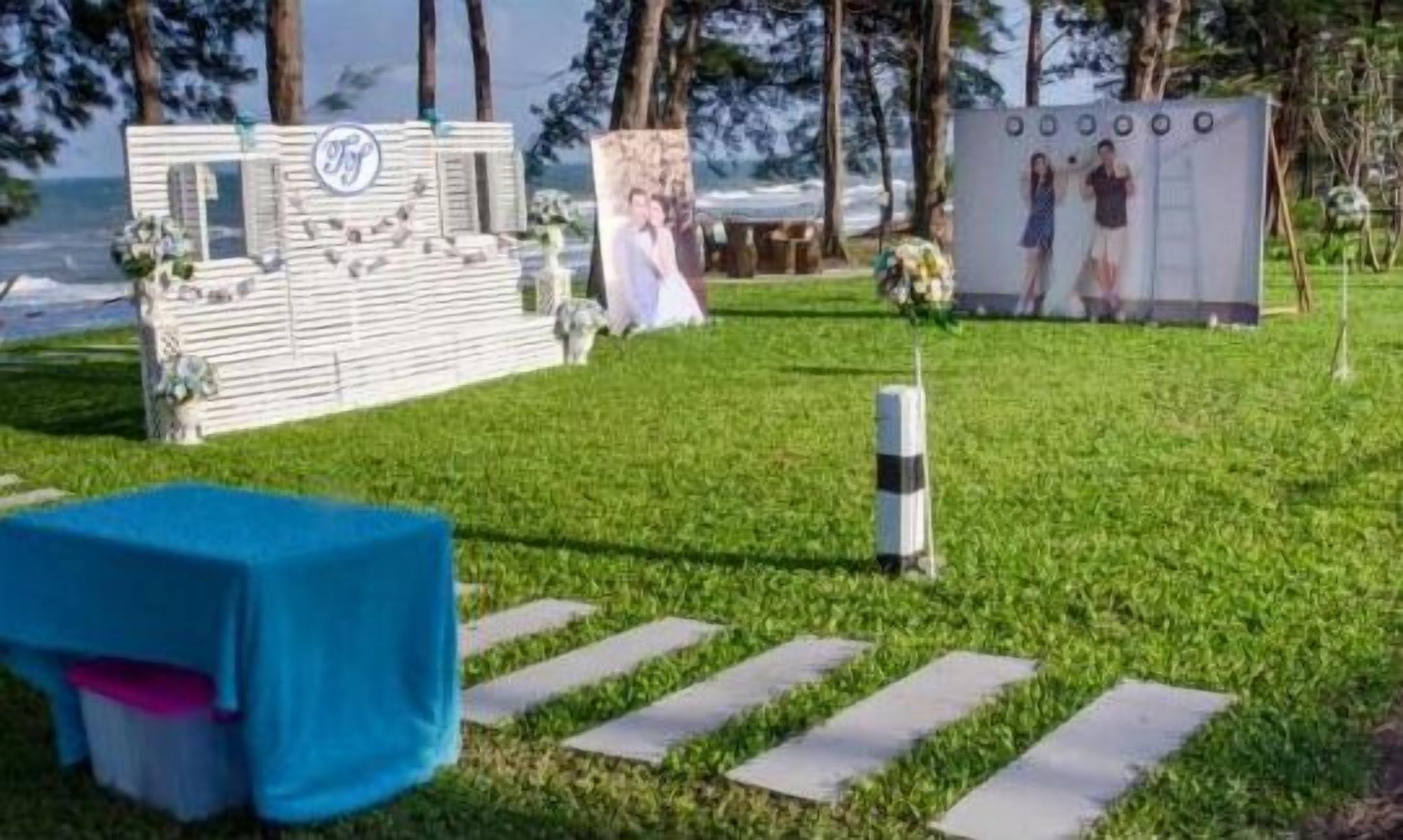 Decoración de boda con un fondo blanco, una mesa azul y un atril para fotos.