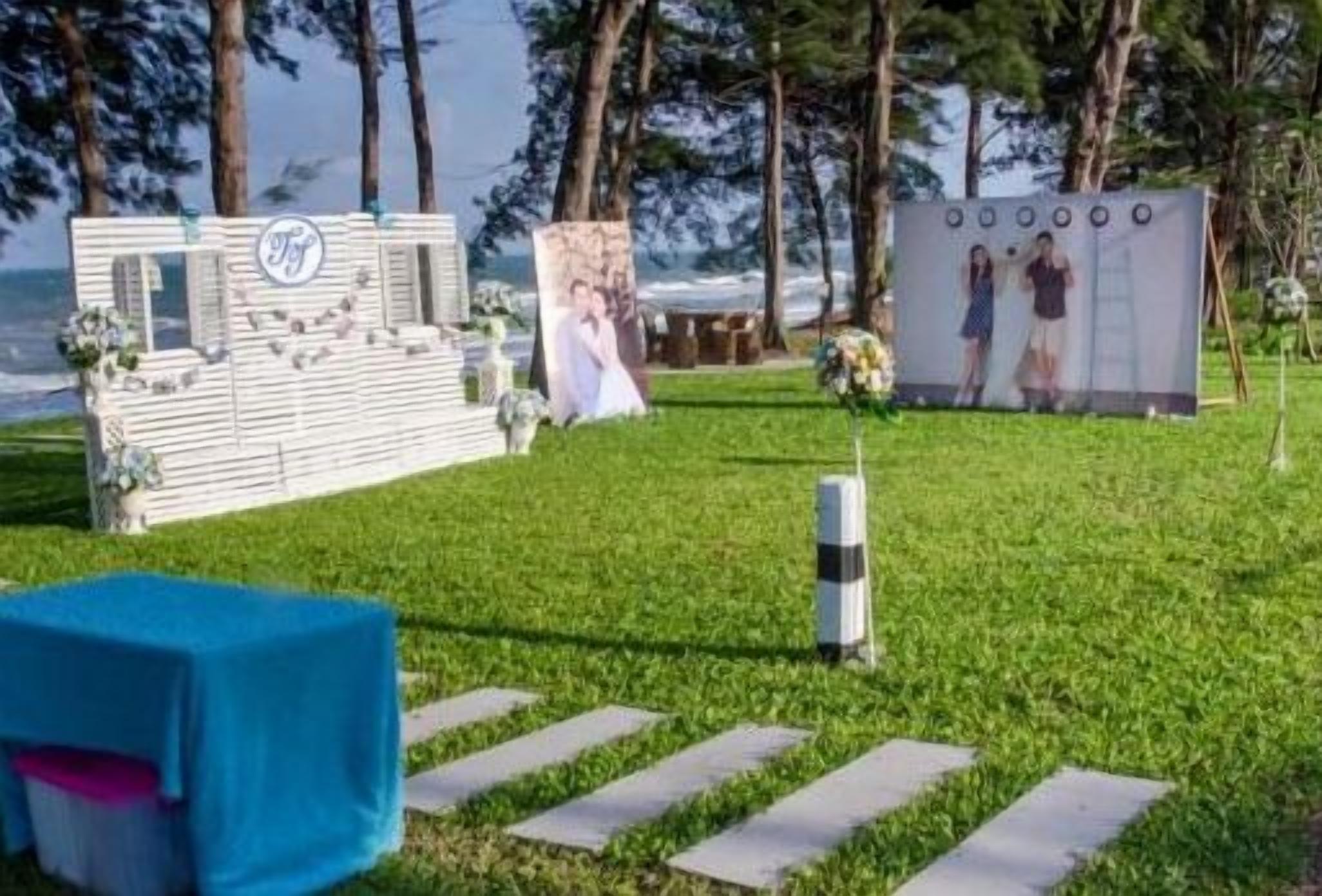Decoración de boda con un telón de fondo blanco, un cartel grande y una mesa azul.