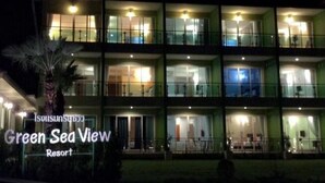 Un hotel de varios pisos llamado Green Sea View Resort, con una entrada bien iluminada y balcones visibles.