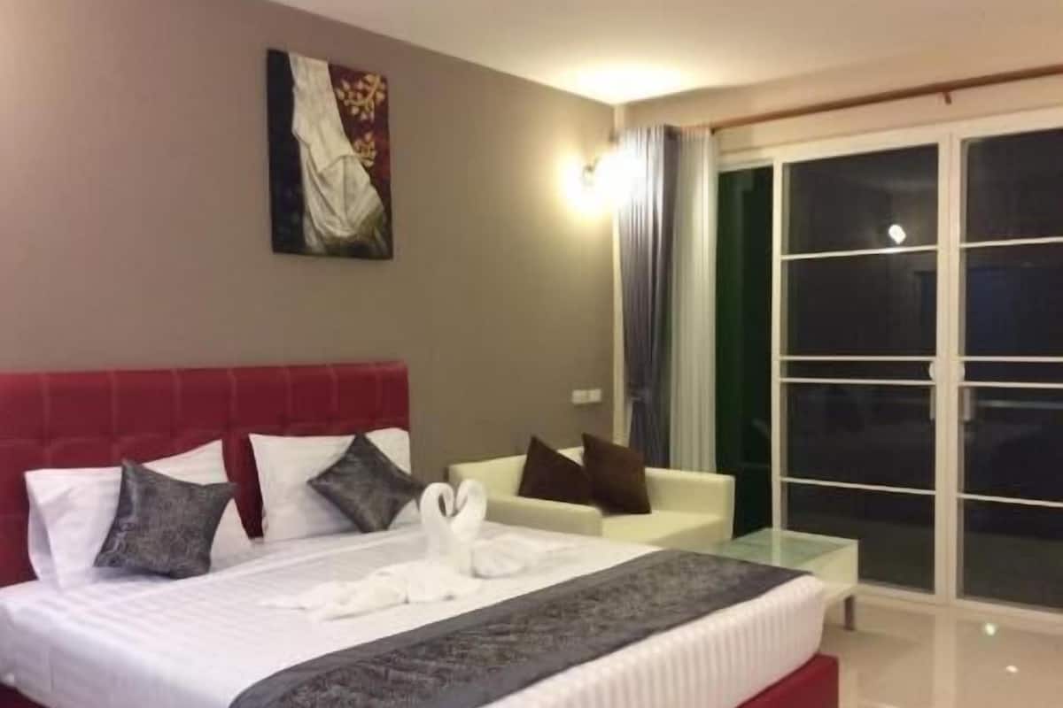 Ett hotellrum med en säng, en vit soffa, en glasdörr som leder ut till en balkong och en tavla på väggen.