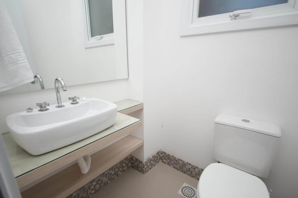 A small, clean bathroom with a white sink, a mirror, and a toilet.