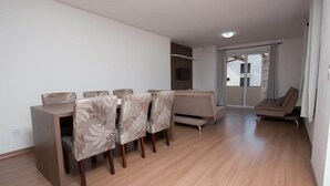 A modern living room with a dining area, a sofa, and a TV. - Residencial Scheifler (Gramado)