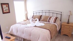 Une chambre à coucher avec un lit, des tables de chevet, une lampe et un tableau encadré au mur.