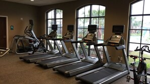 Une salle de sport équipée de tapis de course, de vélos d’appartement et d’autres appareils d’exercice.