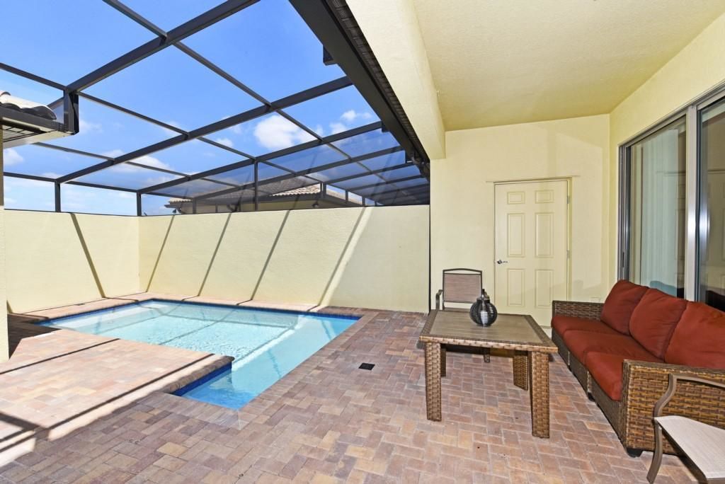 Ein Poolbereich auf dem Dach mit Glasdach, eine Lounge mit Sofa und Tisch sowie eine Tür im Hintergrund.