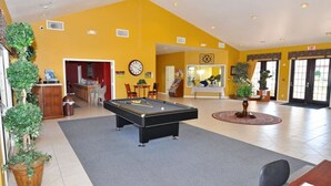 A pool table in a room with yellow walls, a clock, and a door leading to another area. - 211 High Grove House 4 Bedroom by Florida Star (Clermont)