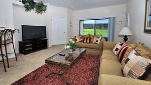 A living room with a television, sofa, coffee table, and a red carpet. - 211 High Grove House 4 Bedroom by Florida Star (Clermont)