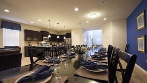 A dining area with a long table set for a meal, surrounded by dark chairs. - 2167 Windsor at Westside House 8 Bedroom by Florida Star (Kissimmee)