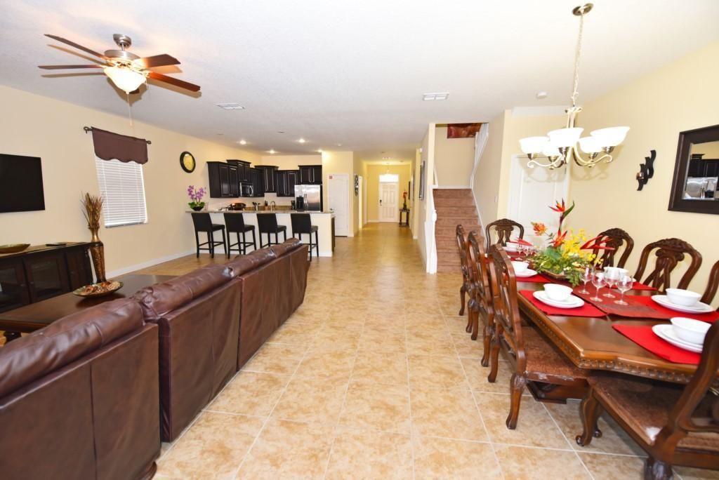 A spacious dining area with a long table, brown leather booth seating, and a kitchen in the background.