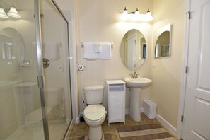 Un baño con cabina de ducha de vidrio, inodoro, lavabo y espejo.
