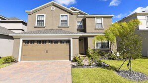 A two-story house with a garage, a well-maintained lawn, and a small tree in the front yard. - 2341 Providence House 6 Bedroom by Florida Star (Davenport)