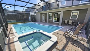 A backyard with a swimming pool and hot tub, surrounded by a covered patio area with chairs. - 2341 Providence House 6 Bedroom by Florida Star (Davenport)