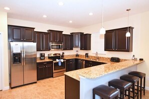 Enjoy cooking in this well-equipped kitchen with a refrigerator, microwave, and oven, plus a spacious island with bar stools.