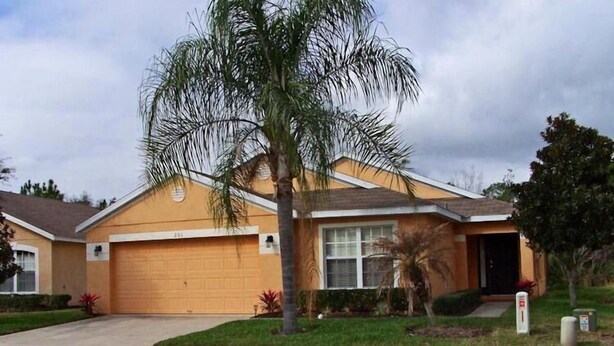 A single-story house with a garage, a front yard, and a palm tree. - 251 Sandy Ridge House 4 Bedroom by Florida Star (Davenport)