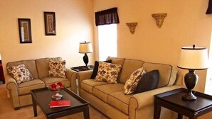 A living room with a beige sofa, two side tables, a coffee table, and a lamp. - 251 Sandy Ridge House 4 Bedroom by Florida Star (Davenport)