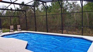 An outdoor swimming pool with a covered area, surrounded by trees. - 251 Sandy Ridge House 4 Bedroom by Florida Star (Davenport)