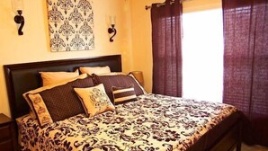 A neatly made bed with patterned bedding, a dark headboard, and two wall-mounted lamps. - 251 Sandy Ridge House 4 Bedroom by Florida Star (Davenport)