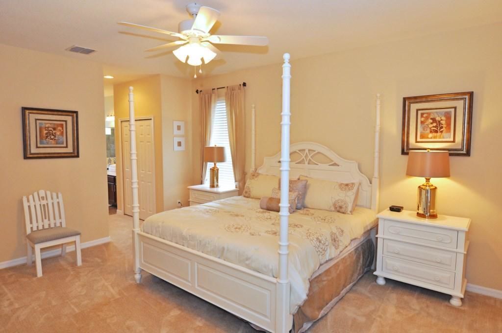 A four-poster bed with a canopy, a bedside table with a lamp, and a chair.