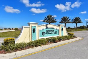 A sign with the name "AKWATER" and a logo, surrounded by landscaping and palm trees. - 2755 Oakwater Condo 2 Bedroom by Florida Star (Kissimmee)