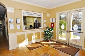 A reception area with a check-in counter, framed certificates on the wall, a potted plant, and a view of the outside through glass doors. - 2809 Windsor Hills Condo 3 Bedroom by Florida Star (Kissimmee)