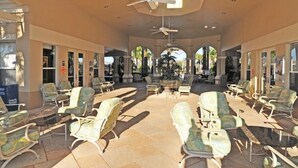 A covered outdoor seating area with chairs and tables, a ceiling fan, and a view of the street. - 2809 Windsor Hills Condo 3 Bedroom by Florida Star (Kissimmee)