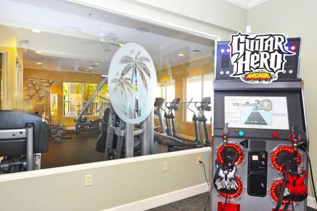 Ein Fitnessraum mit Trainingsgeräten und einem Guitar Hero Arcade-Spiel.