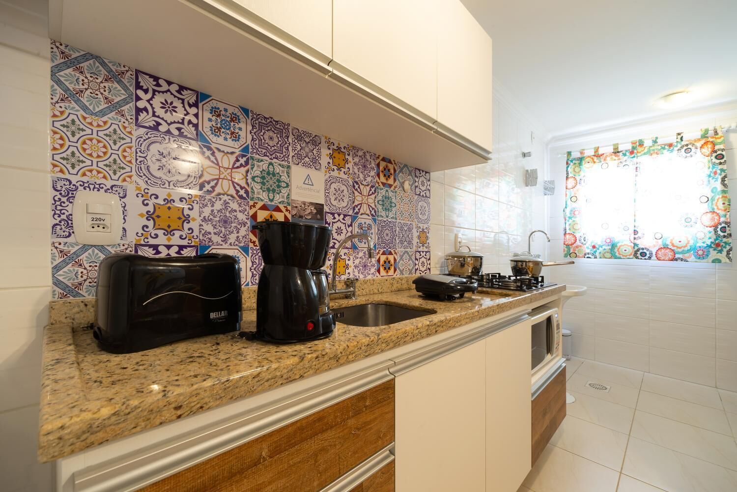 Una cocina con salpicadero de azulejos, un tostador, una cafetera y una estufa.