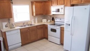 Una cocina con armarios de madera, un refrigerador blanco, un microondas y un lavavajillas.