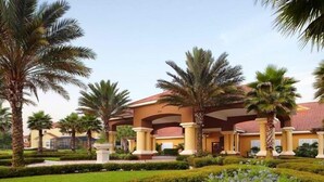 A hotel with a central courtyard, palm trees, and a red-roofed building with columns. - 3010 Encantada House 4 Bedroom by Florida Star (Kissimmee)