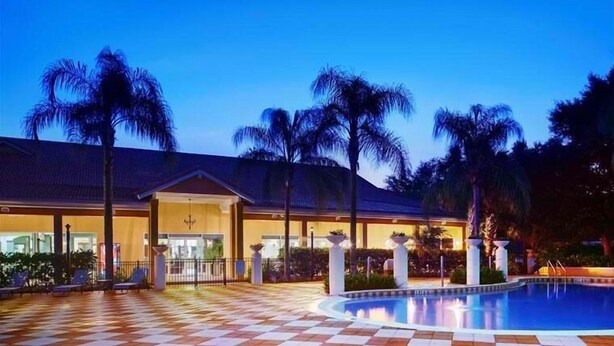 A hotel with a pool, palm trees, and a checkered floor. - 3010 Encantada House 4 Bedroom by Florida Star (Kissimmee)