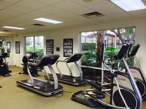 Un gimnasio con cintas de correr, bicicletas estáticas y máquinas de pesas.