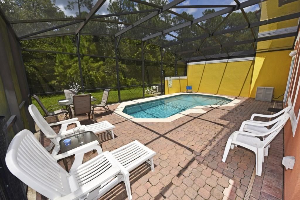 Un espace piscine extérieur abrité, avec des chaises longues blanches, une table et un jacuzzi.