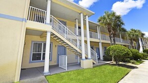 A multi-story building with a central staircase, balconies, and a well-maintained lawn. - 3117 Sun Lake Condo 3 Bedroom by Florida Star (Kissimmee)