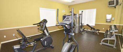 Un gimnasio con máquinas de cardio, bancos de pesas y mancuernas.