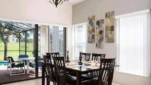 A dining area with a table set for six, surrounded by chairs, and large windows with blinds. - 320 High Grove House 5 Bedroom by Florida Star (Clermont)