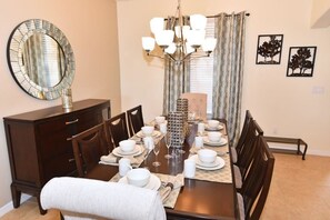 A dining room with a table for six, a large mirror, and a chandelier.