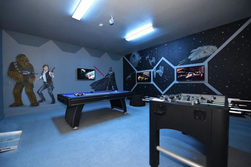 Una habitació amb billar, futbolí i decoració i mural temàtics de Star Wars.