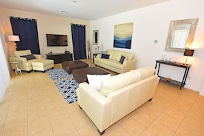 A living room with two cream-colored sofas, a coffee table, a TV, and a patterned rug.