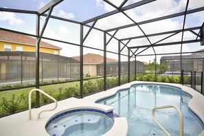An indoor swimming pool with a glass enclosure, surrounded by a metal frame and a view of residential buildings.