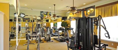 A gym with various exercise equipment, a treadmill, and a ceiling fan.
