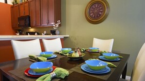 A dining table set with blue and green bowls, plates, and green napkins. - 4452 Veranda Palms House 4 Bedroom by Florida Star (Kissimmee)