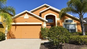 A two-story house with a garage, a small arched window, and a palm tree in the front yard. - 4452 Veranda Palms House 4 Bedroom by Florida Star (Kissimmee)