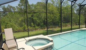A swimming pool with a hot tub, surrounded by a covered area with a view of trees. - 4464 Veranda Palms House 6 Bedroom by Florida Star (Kissimmee)