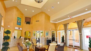 A spacious lobby with a high ceiling, comfortable seating, a reception desk, and large glass doors leading outside. - 4569 Bella Vida Condo 3 Bedroom by Florida Star (Kissimmee)