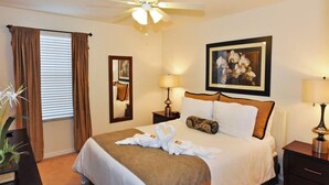 A hotel room with a bed, a ceiling fan, a framed picture, two bedside lamps, and a window with curtains. - 4571 Bella Vida Condo 3 Bedroom by Florida Star (Kissimmee)