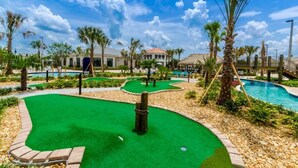 Un parcours de golf doté d’un green d’entraînement, d’une piscine et de palmiers.
